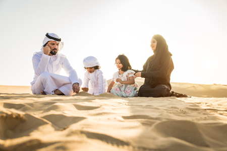 Arabian family with kids having fun in the desert - Parents and children celebrating holiday in the Dubai desrtの写真素材