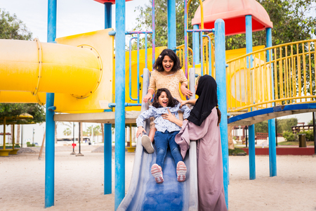 Happy arabian family having fun in Dubai - Mom together with her daughters in park play areaの写真素材