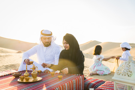 Arabian family with kids having fun in the desert - Parents and children celebrating holiday in the Dubai desertの写真素材