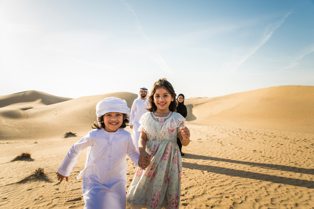 Arabian family with kids having fun in the desert - Parents and children celebrating holiday in the Dubai desrtの写真素材