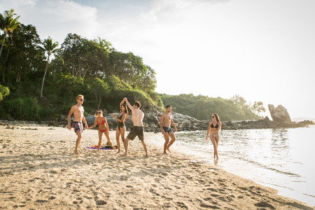 Group of happy friends on a tropical island having fun - Young adults playing together on the beach, summer vacation on a beautiful beachの写真素材