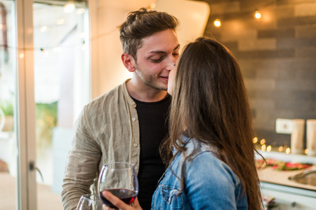 Beautiful young couple of lovers drinking wine at home