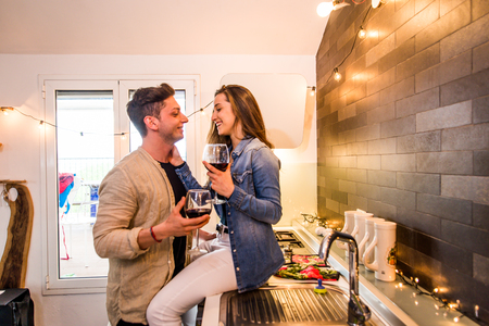 Beautiful young couple of lovers drinking wine at homeの写真素材
