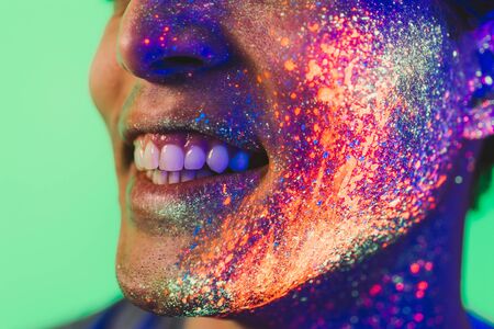 Handsome boy dancing at the rave party with fluorescent paintings on his faceの写真素材