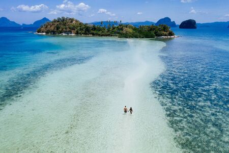 Enjoying the time at the beach. People walking on the white sand, with tropical jungle in the background. Concept about traveling and natureの写真素材