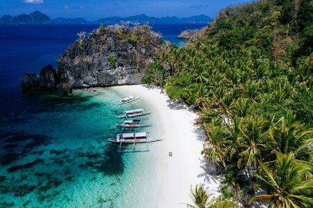 Enjoying the time at the beach. People walking on the white sand, with tropical jungle in the background. Concept about traveling and natureの写真素材