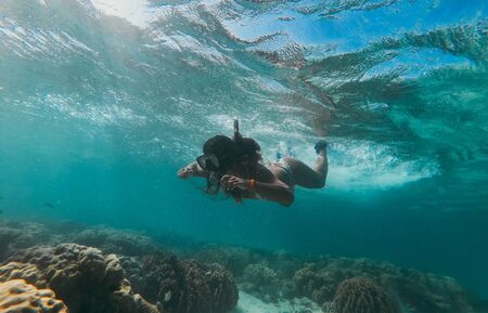 Beautiful woman swimming underwater in a tropical sea full of corals. under water shot with action camera. concept about wanderlust travelsの写真素材