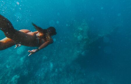 Discovering a japanese ship wreck from second world war. Beautiful woman swimming underwater in a tropical sea. under water shot with action camera.の写真素材