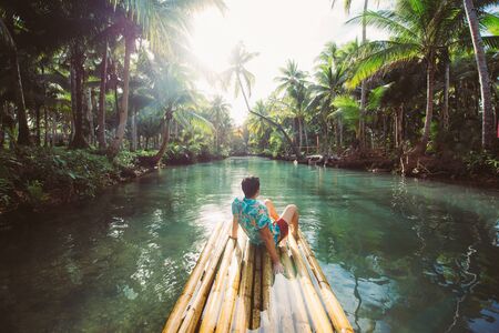 Palm tree jungle in the philippines. concept about wanderlust tropical travels. swinging on the river. People having funの写真素材