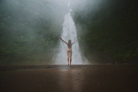 Beautiful girl having fun at the waterfalls in Bali. Concept about wanderlust traveling and...