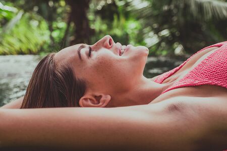 Beautiful girl relaxing outdoor in her garden with swimming pool. Summer concept about lifestyle,beauty, vacations and real estatesの写真素材