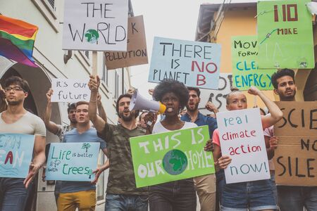Public demonstration on the street against global warming and pollution. Group of multiethnic people making protest about climate change and plastic problems in the oceansの写真素材