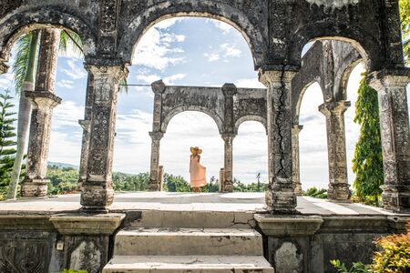 Young beautiful woman in Taman Ujung water palace, Bali island, Indonesiaの写真素材