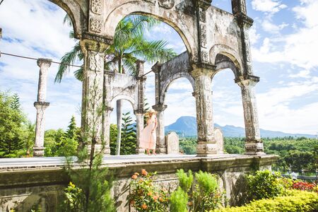 Young beautiful woman in Taman Ujung water palace, Bali island, Indonesiaの写真素材
