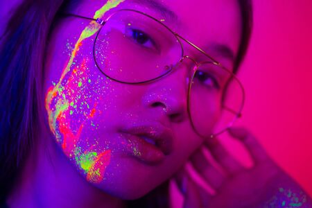 Portrait of fashionable woman with colored  painting on the faceの写真素材