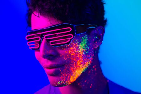 Portrait of fashionable man with colored painting on the faceの写真素材