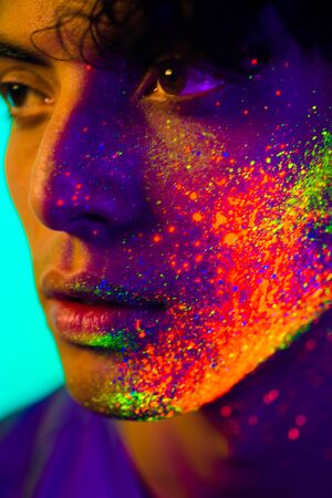 Portrait of fashionable man with colored painting on the faceの写真素材