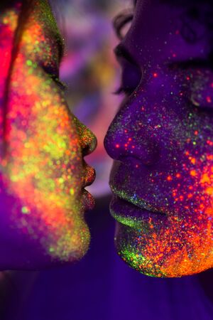 Portrait of fashionable couple  with colored  painting on the faceの写真素材