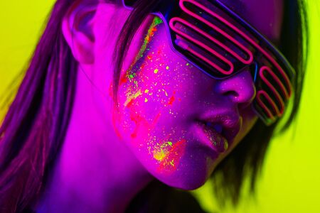 Portrait of fashionable woman with colored fluo painting on the face - Fashion model on colored...