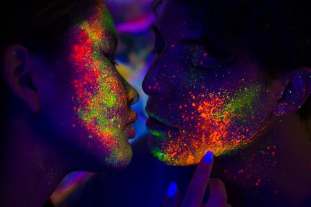 Portrait of fashionable couple  with colored  painting on the face