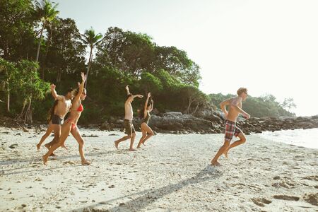 Group of friends having fun on the beach on a lonely island