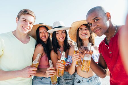 Group of friends spending time on the beach together celebrating. People enjoying the mediterranean...