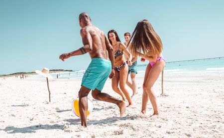 Group of friends spending time on the beach together celebrating. People enjoying the mediterranean...