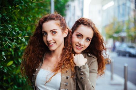 Beautiful twin sisters bonding and having fun outdoorsの写真素材