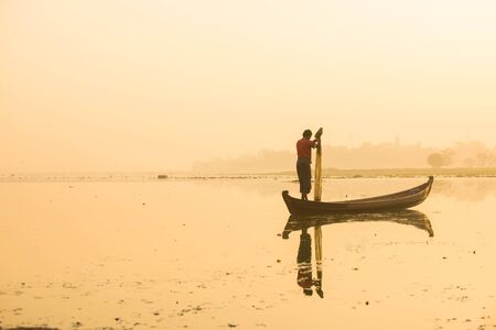 Myanmar fisherman throwing fishing net at lake near U Bein Bridge in Mandalay, Myanmar.の写真素材