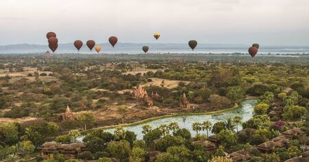 Scenic sunrise with many hot air balloons above Bagan in Myanmar. Bagan is an ancient city with...