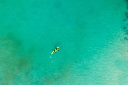 Couple kayaking on a tropical beach with blue waterの写真素材