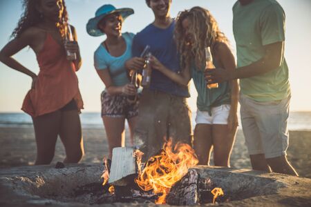 Group of friends having fun on the beach with bonfireの写真素材