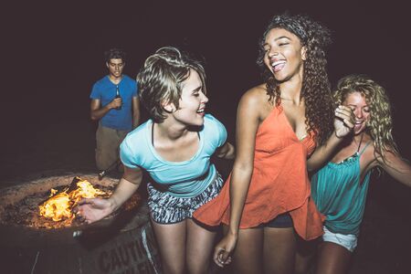 Group of friends having fun on the beach with bonfire
