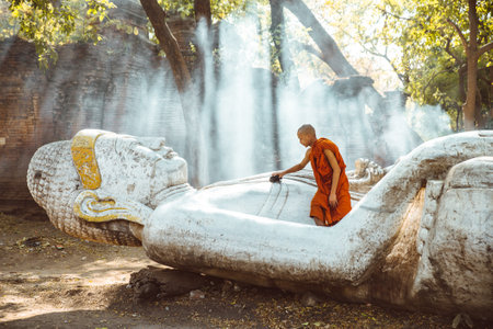 MANDALAY, MYANMAR . MARCH 2ND 2019. Children monk cleaning and praying on the buddha statue. In myanmar childrens start the training to become monks at the age of sevenのeditorial素材