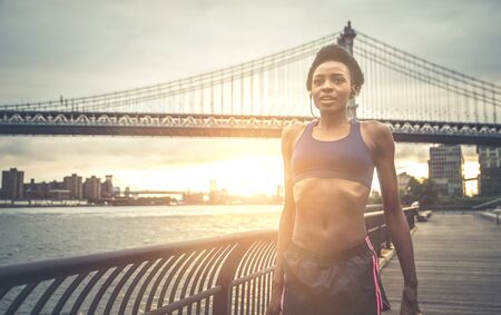 Athlete woman training in the morning at sunrise in New york city, Brooklyn in the backgroundの写真素材