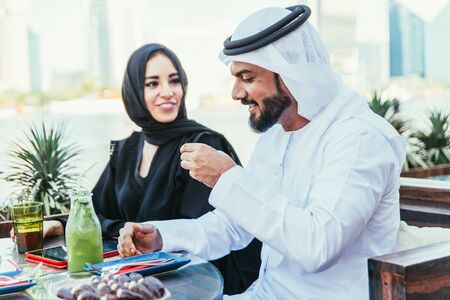 Happy couple spending time in Dubai. man and woman wearing traditional clothes having a conversation in a cafeの写真素材