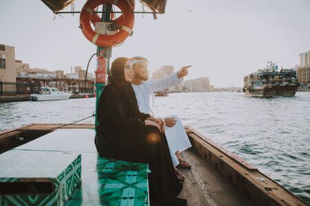 Happy couple spending time in Dubai. man and woman wearing traditional clothes taking a cruise on...