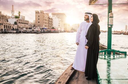 Happy couple spending time in Dubai. man and woman wearing traditional clothes taking a cruise on the riverの写真素材
