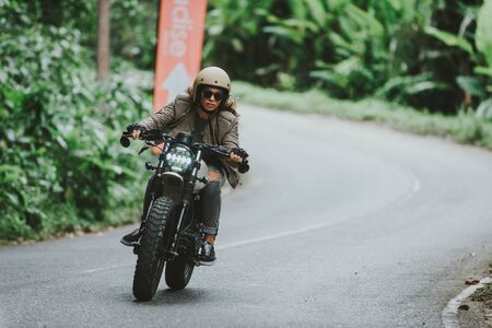 Beautiful girl having fun driving her custom cafe racer motorcycleの写真素材