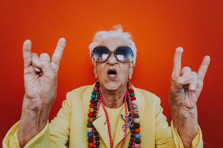 Funny grandmother portraits. Senior old woman dressing elegant for a special event. Rockstar granny on colored backgroundsの写真素材