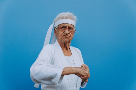 Funny grandmother portraits.granny fashion model on colored backgrounds. Karate master practicing martial artsの写真素材