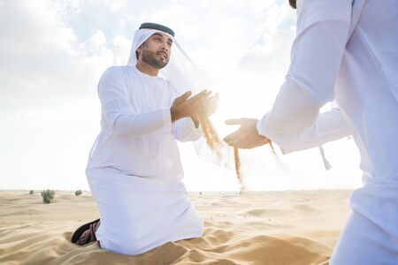 Two business men wearing traditional uae white kandura spending time in the desert of Dubaiの写真素材