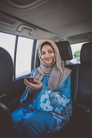 Beautiful woman in Dubai wearing abaya traditional female dress  sitting in the  car. Concept about...
