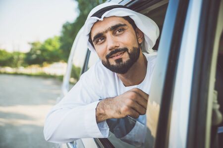 Handsome man with uae traditional outfit driving in Dubai. Middle eastern man with kandura in the...