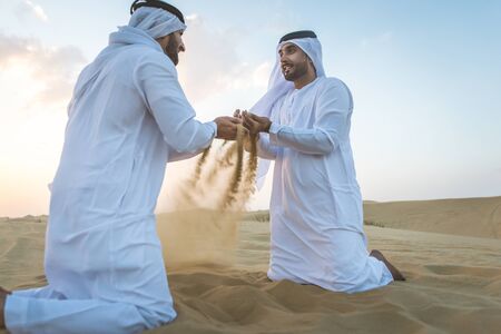 Two business men wearing traditional uae white kandura spending time in the desert of Dubaiの写真素材