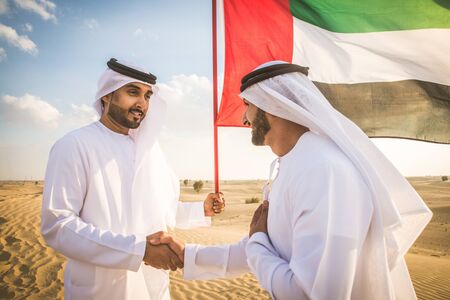 Arabian men witk kandora walking in the desert - Portrait of two middle eastern adults with traditional arabic dressの写真素材