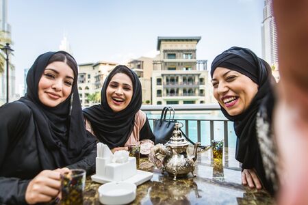 Arabic women with abaya bonding and having fun outdoors - Happy middleastern friends meeting and...