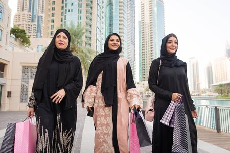 Arabic women with abaya bonding and having fun outdoors - Happy middleastern friends meeting and...