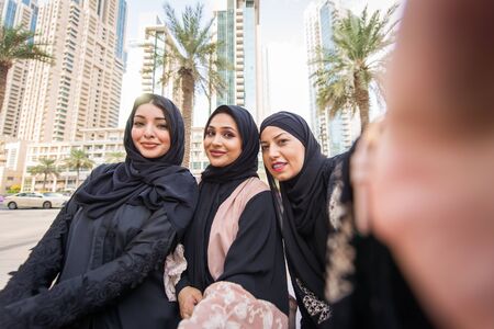 Arabic women with abaya bonding and having fun outdoors - Happy middleastern friends meeting and...
