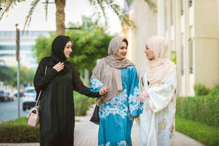 Arabic women with abaya bonding and having fun outdoors - Happy middleastern friends meeting and...